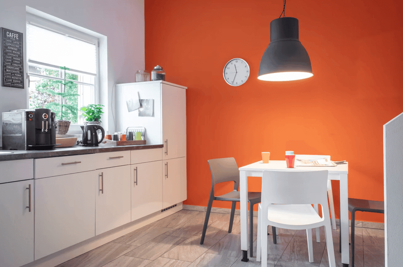 Moderne Küche und Pausenbereich mit orangefarbener Wand